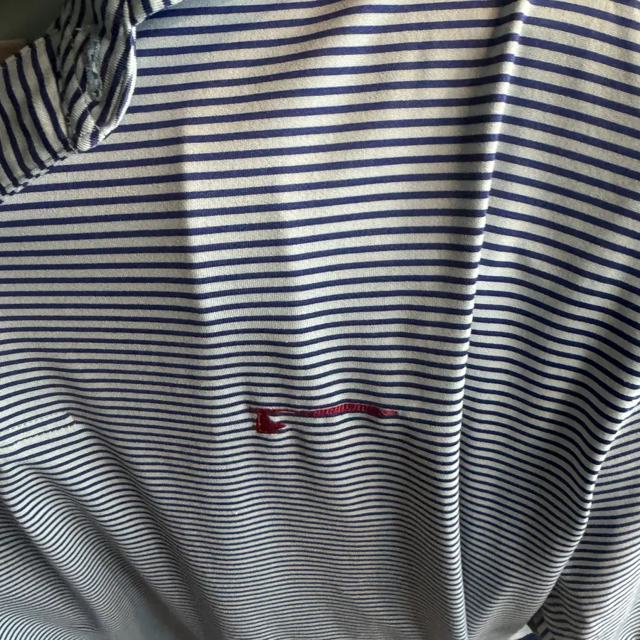 Close-up of a small red golf club logo embroidered on the chest